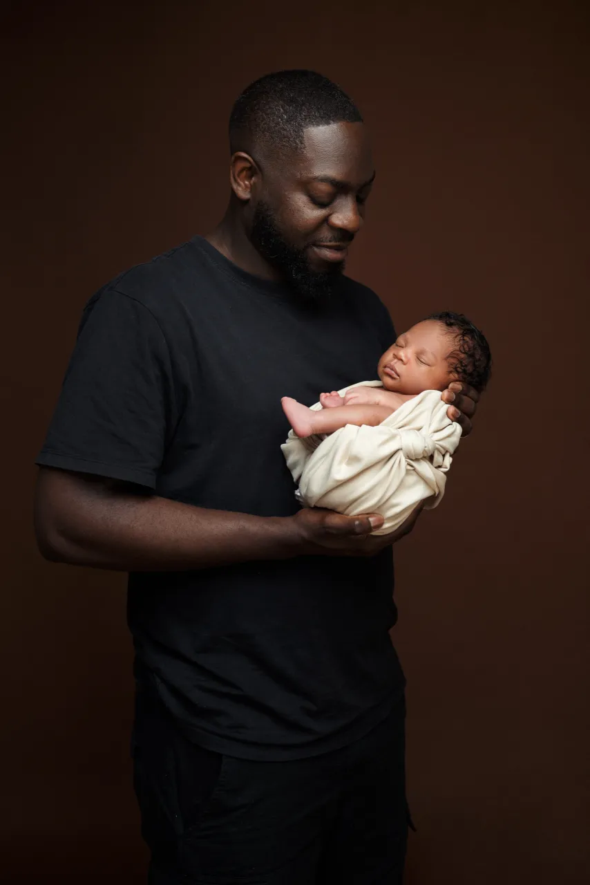 Papa tenant un nouveau-né sur fond brun, Studio Bena