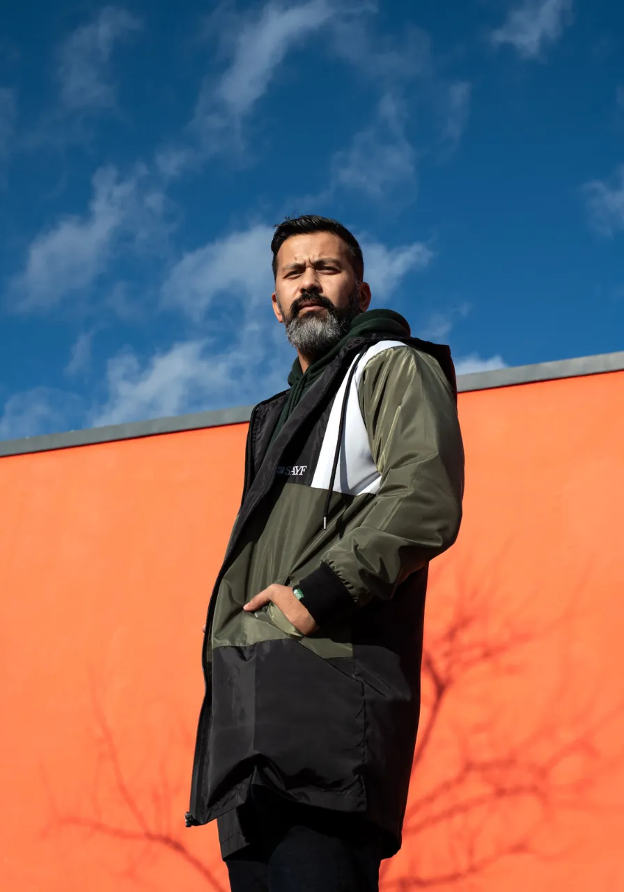 Homme en parka devant un mur orange, Studio Bena